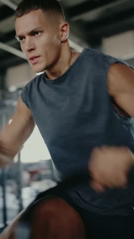 A fit man is intently working out on a stationary bike in a gym, exuding determination and strength as he focuses on his intense cardio session. Focused on Intense Cardio Workout. Vertical