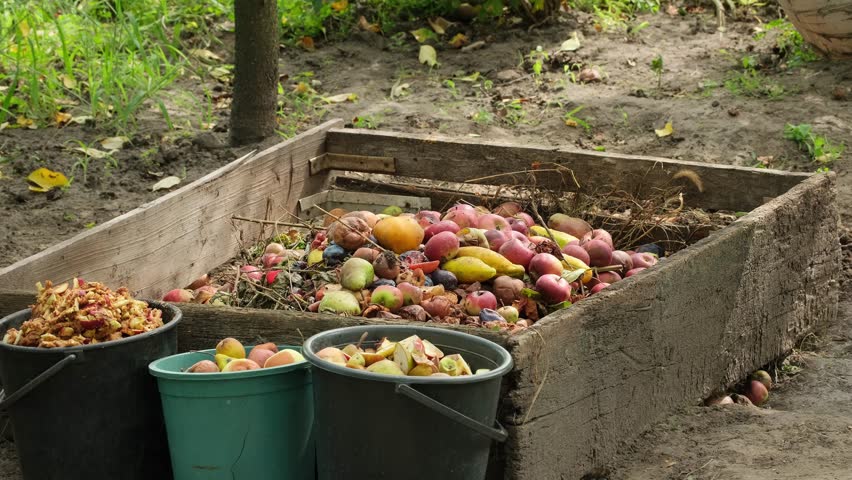 Organic waste falling from a bucket into a compost pit. Bio-waste recycling. Compost bin with organic waste. Bio food waste composting bin. Biodegradable material, organic recycling concept