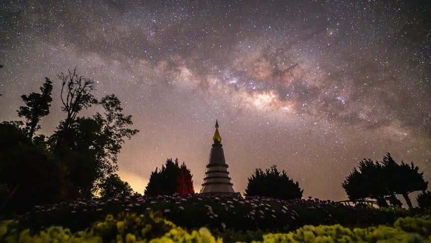 In the center of the Milky Way, with a temple and flowers in the foreground.