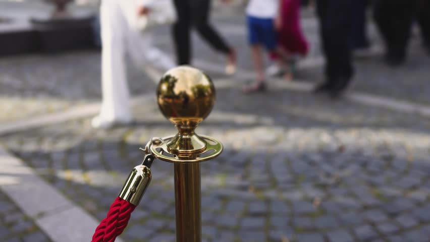 Red carpet with ropes and golden barriers on a luxury party entrance, cinema premiere film festival event award gala ceremony, wealthy rich guests arriving, outdoor decoration elements, summer day