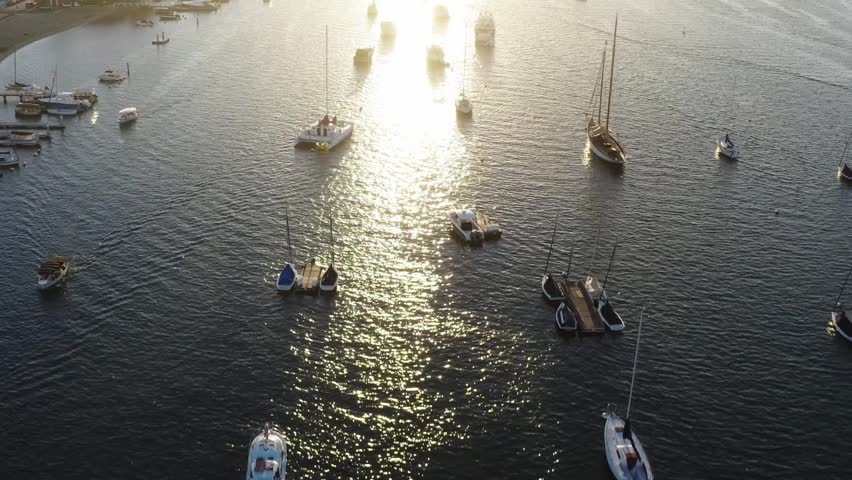 Bird's eye view aerial of sailboats glistening at sunset in Newport Bay, California
