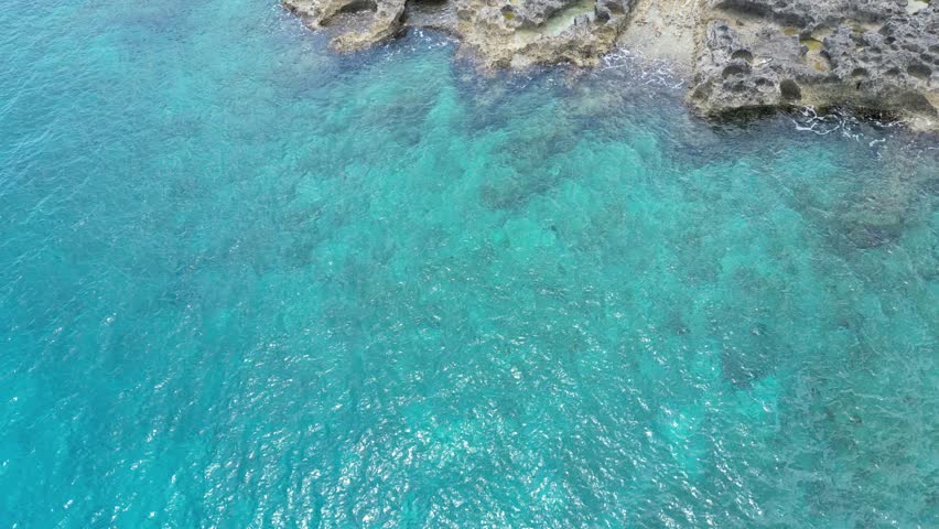 Stunning aerial view of West Bay, located in the western district of Grand Cayman in the Cayman Islands, featuring vibrant blue turquoise Caribbean Sea waters, rugged ironshore beach, and breathtaking