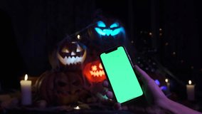Hand holding a phone with chrome key on a Halloween background of many lanterns made of cut out glowing pumpkins - Powered by Shutterstock - Get 15% off with code: PIKWIZARD15