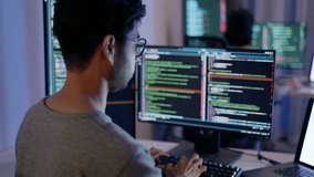 Rear view of a male programmer working on multiple monitors filled with code, highlighting a late work session in a high-tech environment. - Powered by Shutterstock - Get 15% off with code: PIKWIZARD15