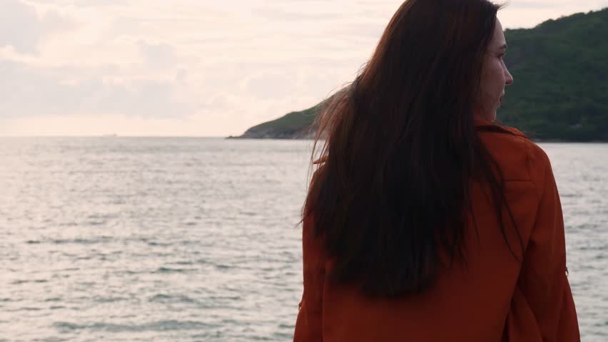 Young girl looking at seascape. Hair fluttering in wind. High quality 4k footage