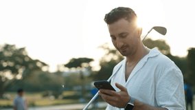 Portrait of golfer reading message on smartphone holding driver on shoulder in sports club. Golf player checks tournament results online via mobile app. Sports betting service - Powered by Shutterstock - Get 15% off with code: PIKWIZARD15