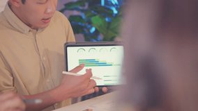 An Asian businessman gives a presentation on renewable energy, holding a tablet during an indoor corporate meeting. - Powered by Shutterstock - Get 15% off with code: PIKWIZARD15