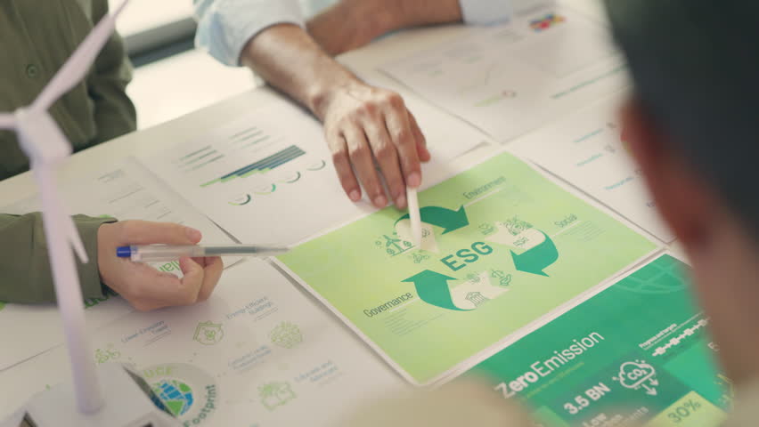 Close-up of a professional's hand pointing to ESG recycling metrics on a printed report during a sustainability strategy meeting.
