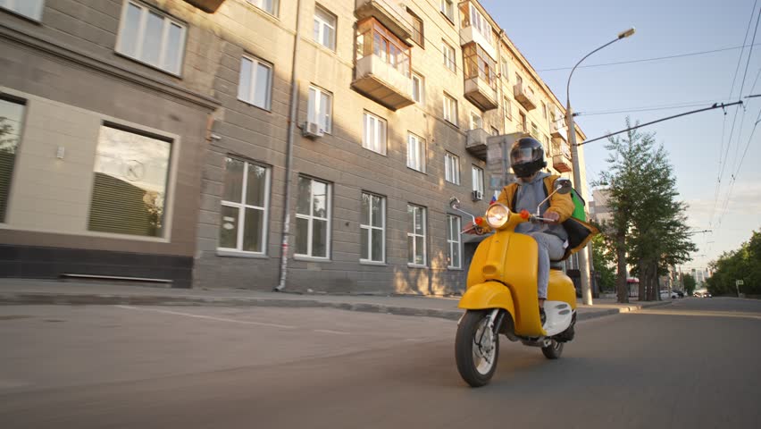 Courier man carry package moped. Guy ride yellow retro scooter city street deliver box in backpack. Fast food delivery service. Person drive bike with store bag. Express home order. Rush rider hurry.
