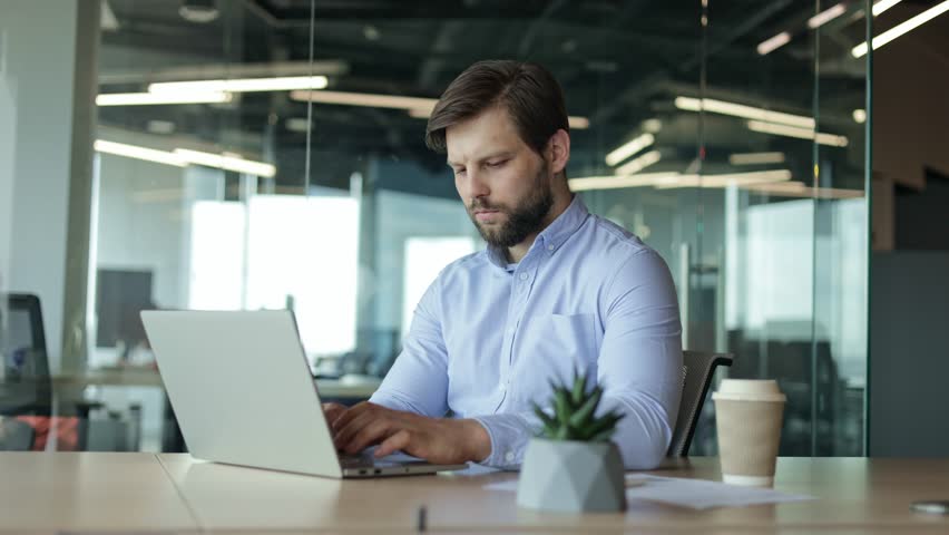 Focused businessman working on laptop computer at his desk in modern office space