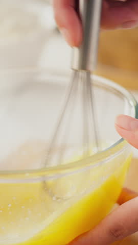 Standing Monitor. Pastry art, European-looking woman slowly whisks egg yolks with a kitchen whisk. Modern woman whipping eggs for cream, showing concern for pregnancy, mixing process
