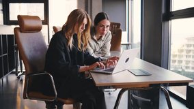 Collaboration in a Modern Workspace Two Women Work Together on a Laptop, Sharing Ideas and Solutions, Highlighting Teamwork and Professional Growth in a Contemporary Setting - Powered by Shutterstock - Get 15% off with code: PIKWIZARD15