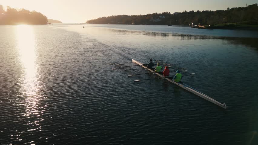 Aerial view Halifax Bay Rowing Crew at Sunrise. A rowing team, captured by a drone, moves gracefully through Halifax Bay at sunrise, their synchronized strokes creating ripples on the water.