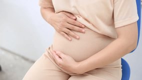 Detail of pregnant woman wearing white clothing and holding her belly with both hands.
 - Powered by Shutterstock - Get 15% off with code: PIKWIZARD15