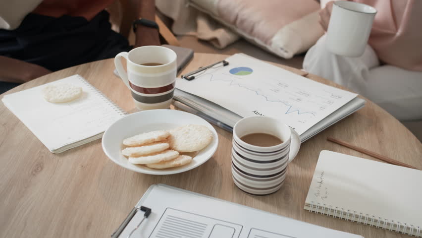 Handheld shot of three business managers drinking coffee and eating snacks during break at office