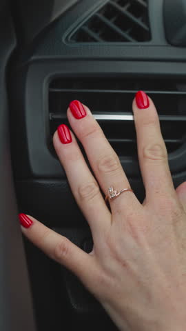 Hand of woman with red nails adjusting air conditioning to stabilize temperature in car. Female driver sits in vehicle turning on cooling system closeup