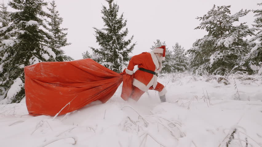 Santa delivering gifts and congratulations to people at Christmas or New Year. Santa Claus with big bag of gifts is late for the holiday, he hurriedly runs through the snow in forest.