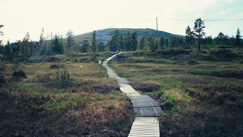 A View of Boardwalks Along a Hiking Path With a Distant Mountain Between iMefjelsvatnet and Gurben in Indre Fosen, Trøndelag, Norway - Handheld Shot