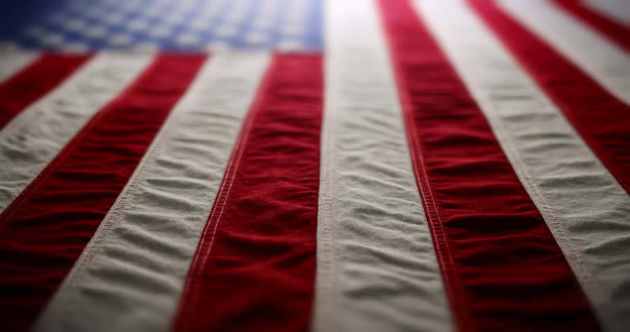 Panning across a brightly lit, red white and blue, US American flag and slowly fading to white. Background for Memorial Day, Veteran's Day, 4th of July, or other patriotic USA holiday.