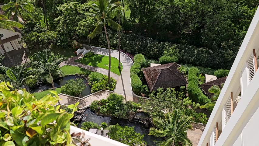 tilt footage of the Pacific ocean with waves, lush green trees, plants and grass, blue sky and clouds on the island of Oahu at the Ko Olina Resort in Kapolei Hawaii USA