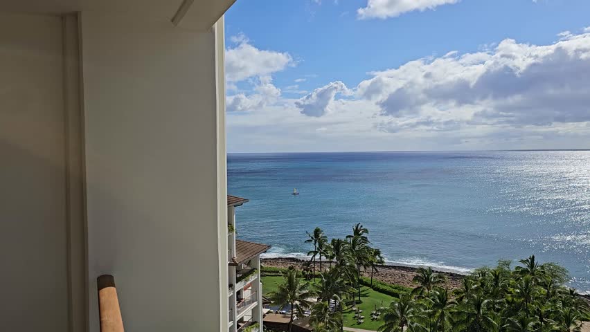 panning footage of the Pacific ocean with waves, lush green trees, plants and grass, blue sky and clouds on the island of Oahu at the Ko Olina Resort in Kapolei Hawaii USA