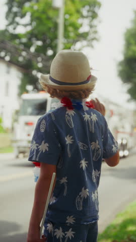 A young boy waves at a fire truck as it drives by, embracing the festive spirit of the fourth of July