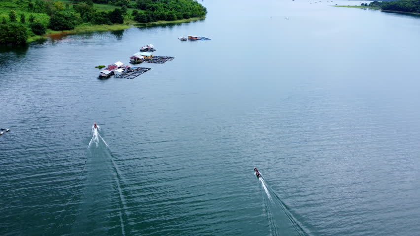 Aerial view of the River Kwai and floating houses in Kanchanaburi Province, Thailand. Beautiful view of floating cottages and Thai long-tail boats sailing on the River Kwai.