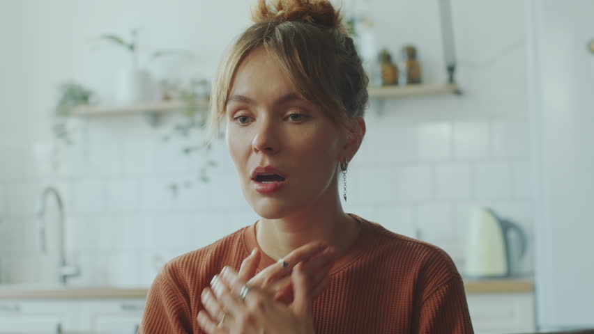 Young feverish woman touching her neck and forehead, suffering from sore throat and headache at home