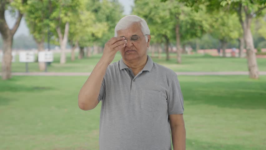 Sick Indian old man having a headache in park