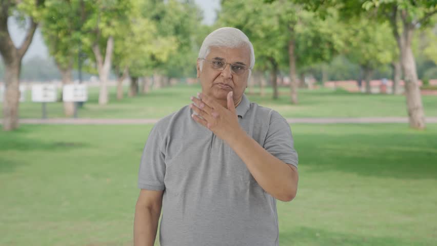 Sick Indian old man suffering from cold and cough in park