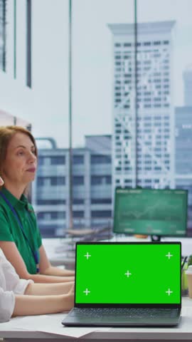 Vertical Video Job seeker attending an interview with the HR team next to mockup screen on laptop, recruiters reviewing qualifications and work experience written in the resume. Employment. Camera B.