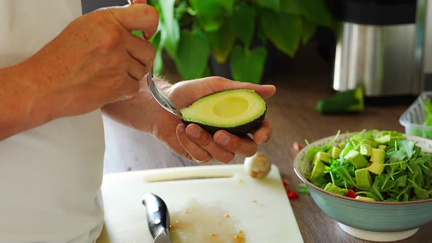 Male hands cutting avocado for fresh salad in home kitchen. High quality 4k footage
