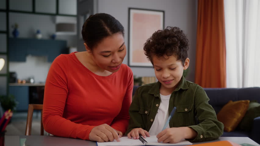 African American family caring mother mom mommy woman babysitter female helping teaching little boy support help love child kid son studying learning homework at home childcare education teach study
