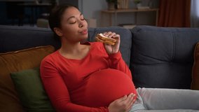 African American girl pregnant woman mother female lady pregnancy child anticipation at home couch sofa waiting baby mom mommy eating sandwich bread eat nutrition food delivery hungry health medicine - Powered by Shutterstock - Get 15% off with code: PIKWIZARD15