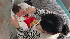 Mother holding newborn baby wrapped in a blanket, baby wearing red pants and yellow socks, capturing a serene bonding moment in a comfortable home environment - Powered by Shutterstock - Get 15% off with code: PIKWIZARD15