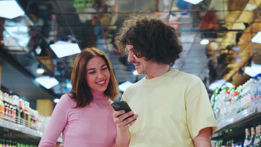 A cheerful couple happily shopping together in a colorful grocery store, enjoying each others company while browsing the vibrant shelves filled with various food products - Powered by Shutterstock - Get 15% off with code: PIKWIZARD15