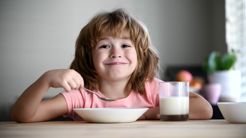 Cute healthy preschool kid boy eats noodles. Kid eating healthy organic food at home. Kids food and drink. Little boy having breakfast in the kitchen.