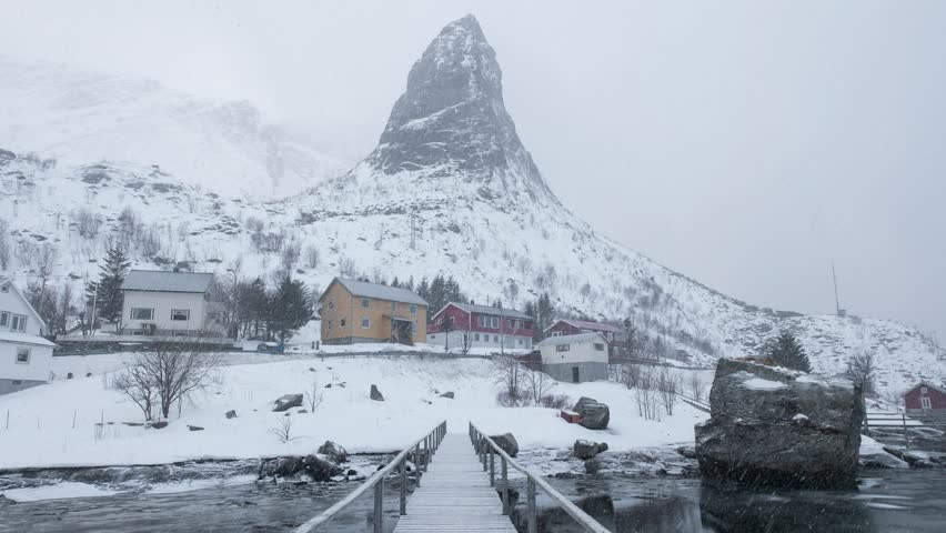 Time lapse of Snow blizzard blowing through fishing village and mountain on wooden bridge at coastline in Lofoten Islands, Norway