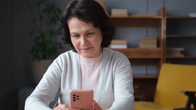 European middle aged senior woman holding using smartphone touch screen typing scroll page. Stylish older mature 60s lady with cell phone using internet social media apps at home. Shopping online - Powered by Shutterstock - Get 15% off with code: PIKWIZARD15