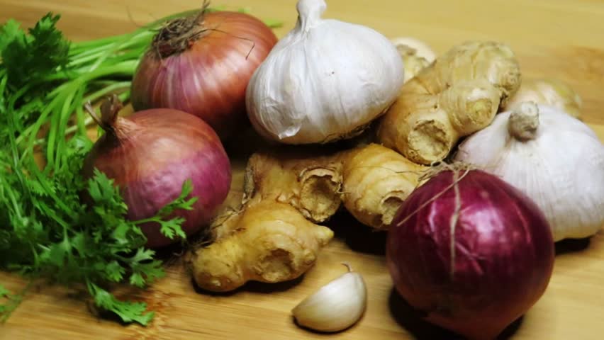 
Pan shot of onion garlic ginger coriander leaf for cooking on a chopping board. Cooking preparation. Nutrition, diet, vegan food concept. Fast food. Burger, Sandwich, pasta.

