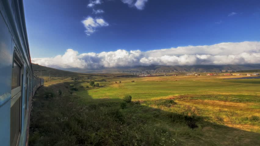 View from the train to a beautiful landscape. Green meadows, clouds, mountains, hills. Lake Sevan, Armenia.