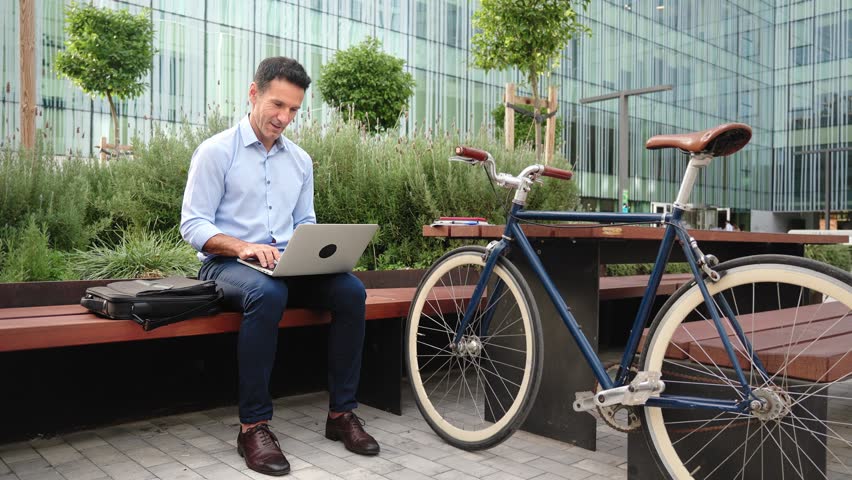 Business man freelancer working on laptop. Modern professional sitting outdoors office with bicycle 