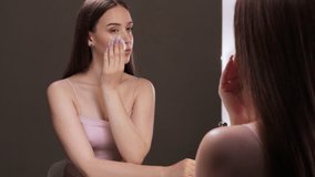 A young beautiful girl removes makeup with a cotton pad and micellar water from her face and eyes. - Powered by Shutterstock - Get 15% off with code: PIKWIZARD15
