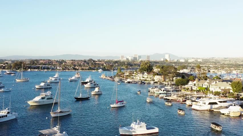 Aerial tracking shot of sailboats in Newport Bay around Bay Island in Newport Beach, California