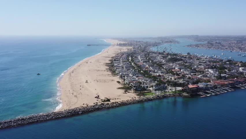 Aerial tracking shot of Balboa Beach and the seaside town of Newport Beach, California