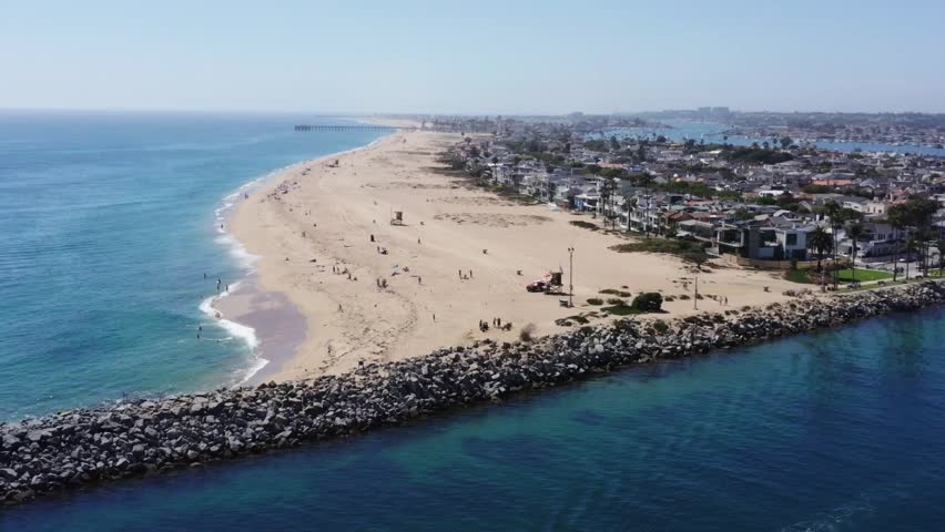 Aerial paralax shot of the jetty at Balboa Beach adjacent to the sunny seaside town of Newport Beach, California