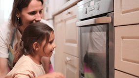 Mother teaching daughter how to use oven in cozy kitchen - Powered by Shutterstock - Get 15% off with code: PIKWIZARD15