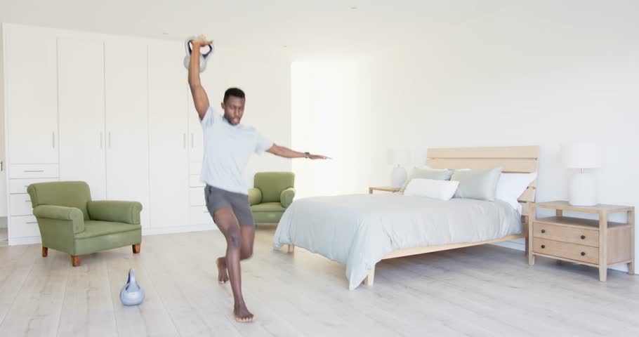 Lifestyle videos indoor of people doing activities at home, exercising with kettlebells, man working out in bedroom for fitness. person working out indoor, working out with weights.
