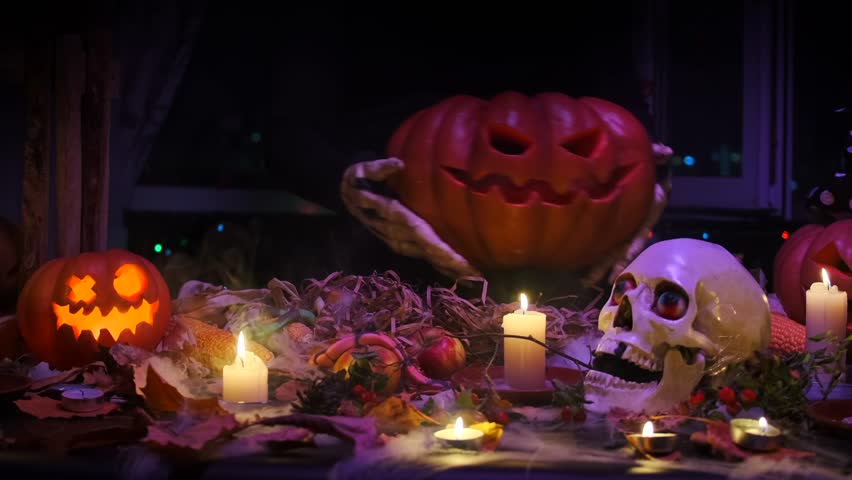 The bony arms of a creepy monster dance with a Halloween pumpkin amidst the fog of skull candles and flickering lights at a party.