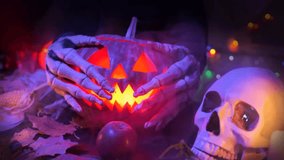 Close-up of witch hands caressing a carved spooky Halloween pumpkin in cold smoke next to a human skull with a burning candle and an apple among dry foliage. - Powered by Shutterstock - Get 15% off with code: PIKWIZARD15